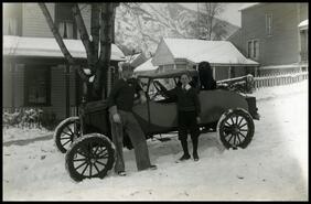 Two boys with car in front of 909 Vernon St. in winter