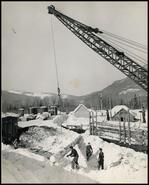 Men loading logs in the Arrowhead Wood Preserves Company yard on the Columbia River in winter