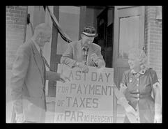 Hattie Jacques, Harry Logan and W.H. Logan in front of the Enderby City Hall with tax sign