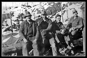Four miners posing on log
