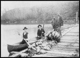 Group with canoe at dock returning from a hunting trip