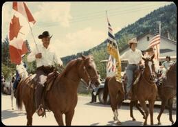 Eddie King and unidentified with flags leading Falkland Stampede parade on horseback