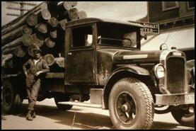Man leaning against loaded logging truck