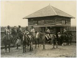 Women on horseback in front of blockhouse during the opening of David Thompson Memorial Fort