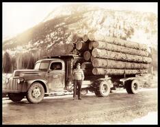 Unidentified man in front of loaded L.E. Lewis logging truck