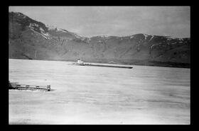 Tug and barge breaking ice on lake, Okanagan Landing