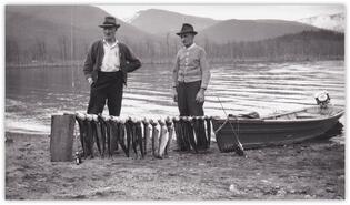 Bill Fraser and unidentified man with fish catch on shore