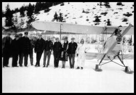 Group with pilot standing by plane in winter