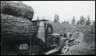 Early Dodge logging truck being assisted by builders