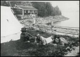 Apple pickers laying on grass at Canoe Point Lake, late 1920s