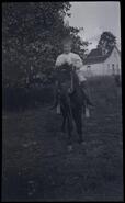 Child on a horse with the Log House in the background