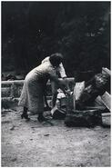 Mrs. O. McGuinness splitting fire wood at Radium Hot springs