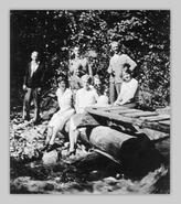 Group including Johnny Hassard at Sunday picnic by a creek