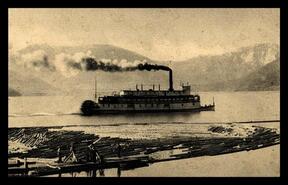 Men on dock with log boom with S.S. Minto at Nakusp