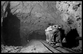 Miner with railcar in tunnel at Base Metal Mine