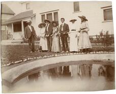 [Group photograph beside ornamental pool by house]