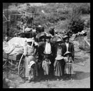 Indigenous group standing beside a loaded wagon