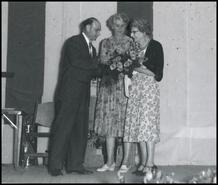 Bino Erickson on stage presenting flowers to Ethel Cleland and Gladys Pitts