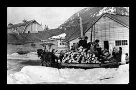 Horses hauling a load of wood and men in winter at Tashme Japanese internment camp