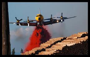 Water bomber dropping retardant on chip and log piles