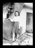 Unidentified young woman posing beside huge tree stump