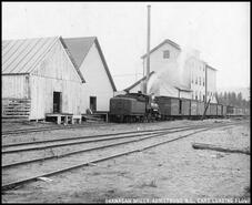 C.P.R. engine and boxcars sitting beside the Armstrong Okanagan Mills being loaded with flour bags