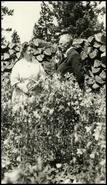 Mr. and Mrs. B.G. Hamilton in front of wood pile