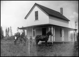 Unidentified man in horse and buggy in front of house in Armstrong