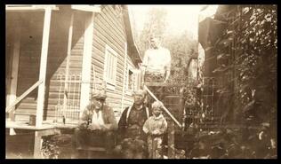 Family sitting on front steps of house at Blakeburn, Coalmont