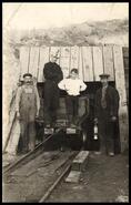 Young boy and three miners outside mine entrance 