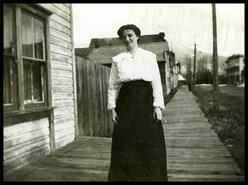 Unidentified woman on wooden sidewalk, Front Street