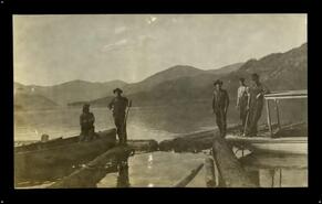 Five men with log boom and boats on Christina Lake