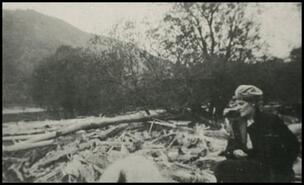 Unidentified woman sitting on driftwood at mouth of Eagle River