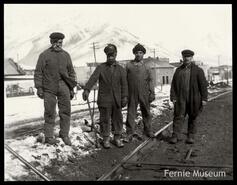Four railway workers laying track