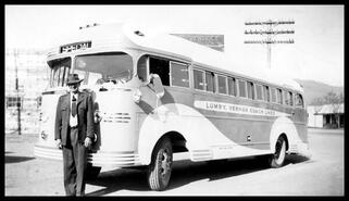 Thomas Henry Chamings standing beside his Lumby-Vernon Coach Lines bus at Peebles Motors in Nelson, B.C.