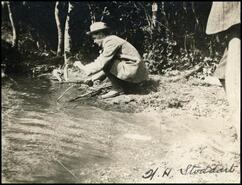 Walter H. Stoddart squatting down by creek