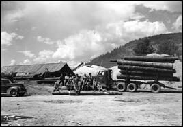 Mill workers at the Francis Barnes lumberyard in Lumby sitting on logs beside a full logging truck