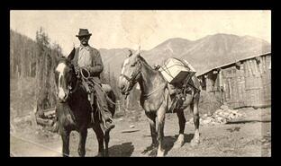 Jim Hill on horseback with pack horse