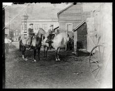 Two riders on horseback outside the Russel Hotel, Grand Forks