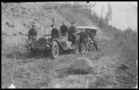 Group of men with two automobiles on a dirt road 12 miles out of Quesnel