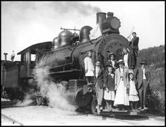 Family standing on the cowcatcher of a railway engine