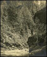 Unidentified man standing on rock ledge beside Anyox River