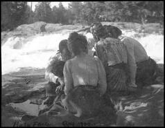 Unidentified people sitting by a river