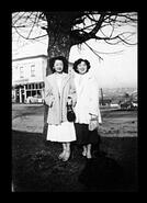 Two unidentified women standing in front of tree