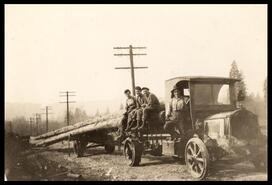 Group of men on truck hauling long poles