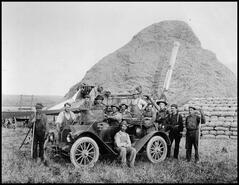 Coldstream Ranch threshing crew around an automobile with the threshing machine in the background