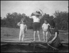 Unidentified woman and children in bathing suits on a wharf