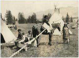 Children in travois behind horse at Indigenous camp during the opening of David Thompson Memorial Fort