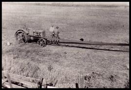Two men standing by tractor ready to run thresher at Eldorado ranch