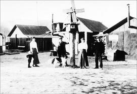 Family at Vernon's internment camp in front of canvas-roofed houses